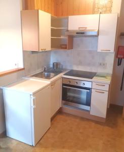 een keuken met witte kasten, een wastafel en een fornuis bij Haus Grünberg in Finkenberg