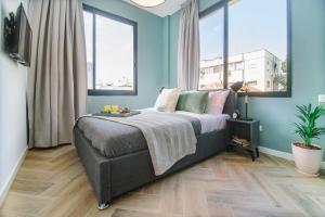 een slaapkamer met een bed met blauwe muren en ramen bij Monochrome Rothschild - Smart Hotel by Loginn Tel Aviv in Tel Aviv