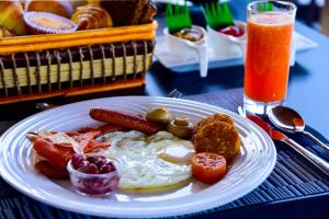 a plate of breakfast food on a table with a drink at Pine Hill Residence in Kandy