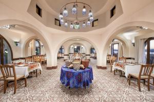 una sala da pranzo con tavoli, sedie e lampadario a braccio di Iberotel Luxor a Luxor