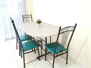 een eettafel met vier stoelen en een tafel met een plant erop bij Pangkor Coral Bay Resort(2 bedrooms) in Pangkor