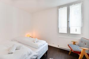 a white bedroom with a bed and a chair at Allure - 2 bedroom apartment with balcony in the centre of Annecy in Annecy