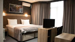 Home Suites Baku-Halal Hotel في باكو: غرفة فندقية بسرير وتلفزيون بشاشة مسطحة