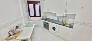 eine weiße Küche mit einem Waschbecken und einer Waschmaschine in der Unterkunft Cozy Yellow Home in Getxo in Getxo