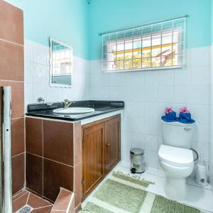 a bathroom with a toilet and a sink and a window at Beau Vallon Residence in Mahe
