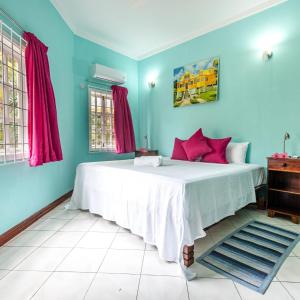 1 dormitorio con 1 cama grande y paredes azules en Beau Vallon Residence en Mahe