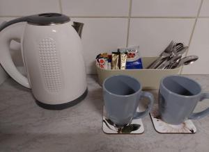 two coffee cups and a tea kettle on a counter at Floret Cottage in Welkom