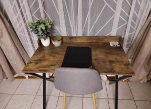a wooden table with a chair and a laptop on it at Floret Cottage in Welkom