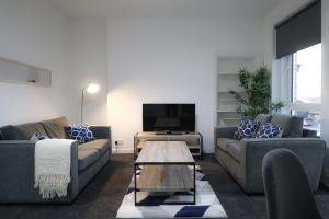 uma sala de estar com dois sofás e uma televisão em Troon Golf Apartment em Troon