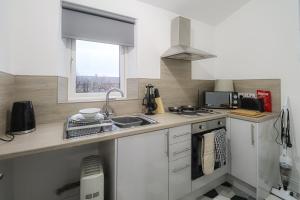 a kitchen with white cabinets and a sink and a window at Troon Golf Apartment in Troon +3 photos