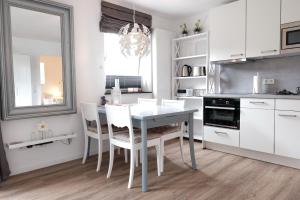 a kitchen with a white table and white chairs at fewo1846 Strandresidenz Wassersleben - Muschelnest - Stilvolles Studioapartment mit Balkon in Harrislee