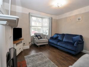 ein Wohnzimmer mit einem blauen Sofa und einem Fernseher in der Unterkunft Hunny Cottage in Hunstanton