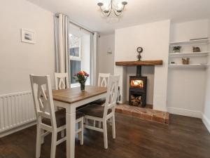 ein Esszimmer mit Tisch und Stühlen und einem Kamin in der Unterkunft Hunny Cottage in Hunstanton