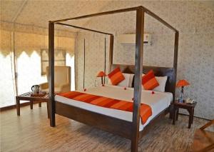 a bedroom with a canopy bed with orange and white pillows at Sultan Bagh Resort by The Sky Imperial in Sawāi Mādhopur