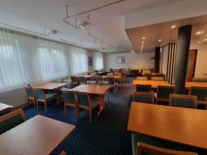 a dining room with tables and chairs and windows at InTeck Hotel in Dettingen unter Teck