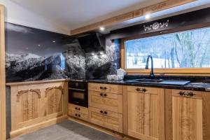 eine Küche mit Holzschränken und Spüle und einem Fenster in der Unterkunft udanypobyt Domki Przy Potoku in Zakopane