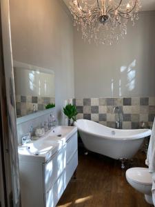 ein Badezimmer mit zwei Waschbecken, einer Badewanne und einem Kronleuchter in der Unterkunft Vieille rose in Niort
