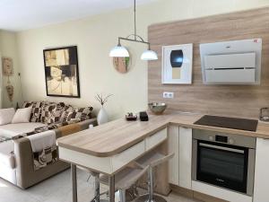 eine Küche und ein Wohnzimmer mit einem Tisch und einem Sofa in der Unterkunft Apartamento Las Vistas Beach - Tenerife Royal Gardens in Playa de las Americas