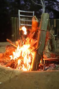 a fire with a chair in front of it at Omya Forest Camps & Cottages Bir, Near Choti Machiyal in Bīr