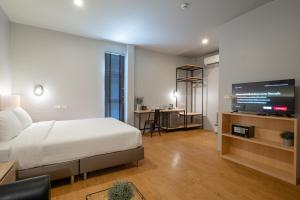 a bedroom with a bed and a flat screen tv at The Arbern Hotel x Bistro - SHA Extra Plus in Phuket