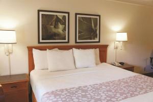 a hotel room with a bed with two pictures on the wall at Baymont by Wyndham Houston La Porte in La Porte