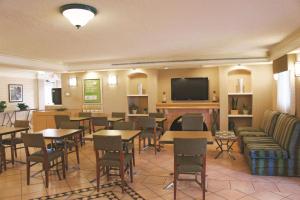 a restaurant with tables and chairs and a flat screen tv at Baymont by Wyndham Houston La Porte in La Porte