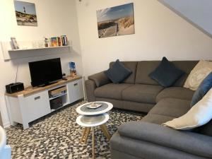 a living room with a couch and a tv at 50040 FeWo kleine Nordseeliebe in Altfunnixsiel
