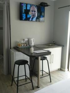a kitchen with a table and stools with a tv on the wall at Eland Place Self Catering Guest House in Beacon Bay