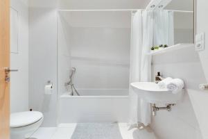 uma casa de banho branca com um lavatório e um chuveiro em JT's Apartments Korunní str. em Praga