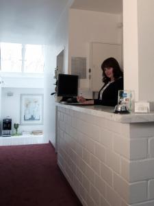 a woman standing in front of a counter with a laptop at Hotel Villa Casa in Düsseldorf