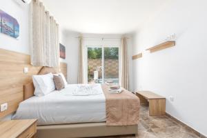 a white bedroom with a bed and a window at Paradise Garden in Kolymbia