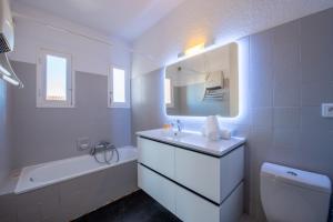 La salle de bains blanche est pourvue d'un lavabo, d'une baignoire et d'un miroir. dans l'établissement Nice Apt Near Bouillabaisse Beach, à Saint-Tropez