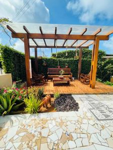 a wooden pergola with a bench and a fire pit at Casa da Laninha in Fernando de Noronha