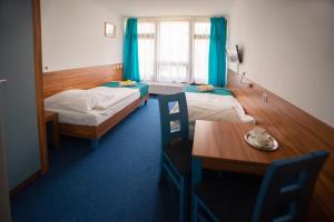 a room with two beds and a table and a dining room at Dom Wczasowy Jawor in Ustroń