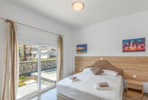 een slaapkamer met een bed en een groot raam bij Paradise Garden in Kolimbia
