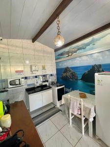 a kitchen with a table and a painting on the wall at Casa da Laninha in Fernando de Noronha