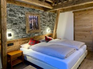 a bedroom with a large bed and a stone wall at Hotel Genziana in Arabba