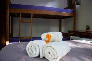 a bed with a pile of towels and a bunk bed at Pousada Tatu do Bem in Lençóis
