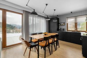 cocina y comedor con mesa de madera y sillas en Tylko Tu i Teraz- Sauna, Balia z jacuzzi, Bon turystyczny, en Baligród