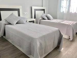 a bedroom with two beds with white sheets at Luxury Attics Avenida Italia PARKING INCLUIDO in Huelva