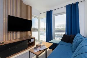 a living room with a blue couch and a flat screen tv at Ostoya Pucka Apartament by Noclegi Renters in Puck