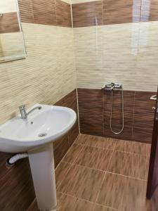 La salle de bains est pourvue d'un lavabo blanc et d'une douche. dans l'établissement Винарна-Славовица, à Kalugerovo