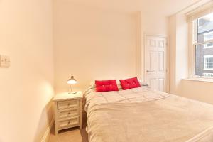um quarto com uma cama com almofadas vermelhas em Penshaw Boutique Apartment em Sunderland
