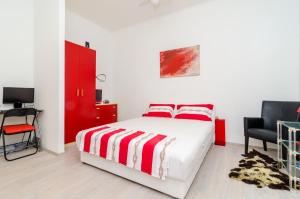 a bedroom with a red and white bed and a chair at Apartment Caceris in Dubrovnik