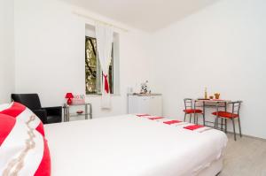 a white bedroom with a large bed and a table at Apartment Caceris in Dubrovnik