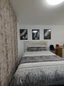 a bed in a bedroom with four pictures on the wall at Intime by Nights & Smiles in Tuzla