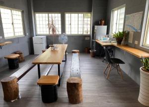 a room with a table and wooden stools and windows at Line Weaving House B&B in Taimali