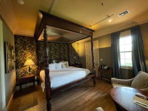 a bedroom with a canopy bed with floral wallpaper at The Inn at Houmas House Estate in Darrow