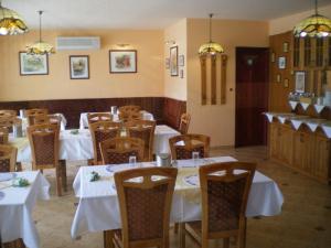 a dining room with tables and chairs with white tablecloths at Mediterrán-Apartmanok-Harkány in Harkány