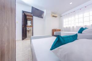 a bedroom with two beds and a tv on the wall at Ayenda Villa Marta in Cartagena de Indias